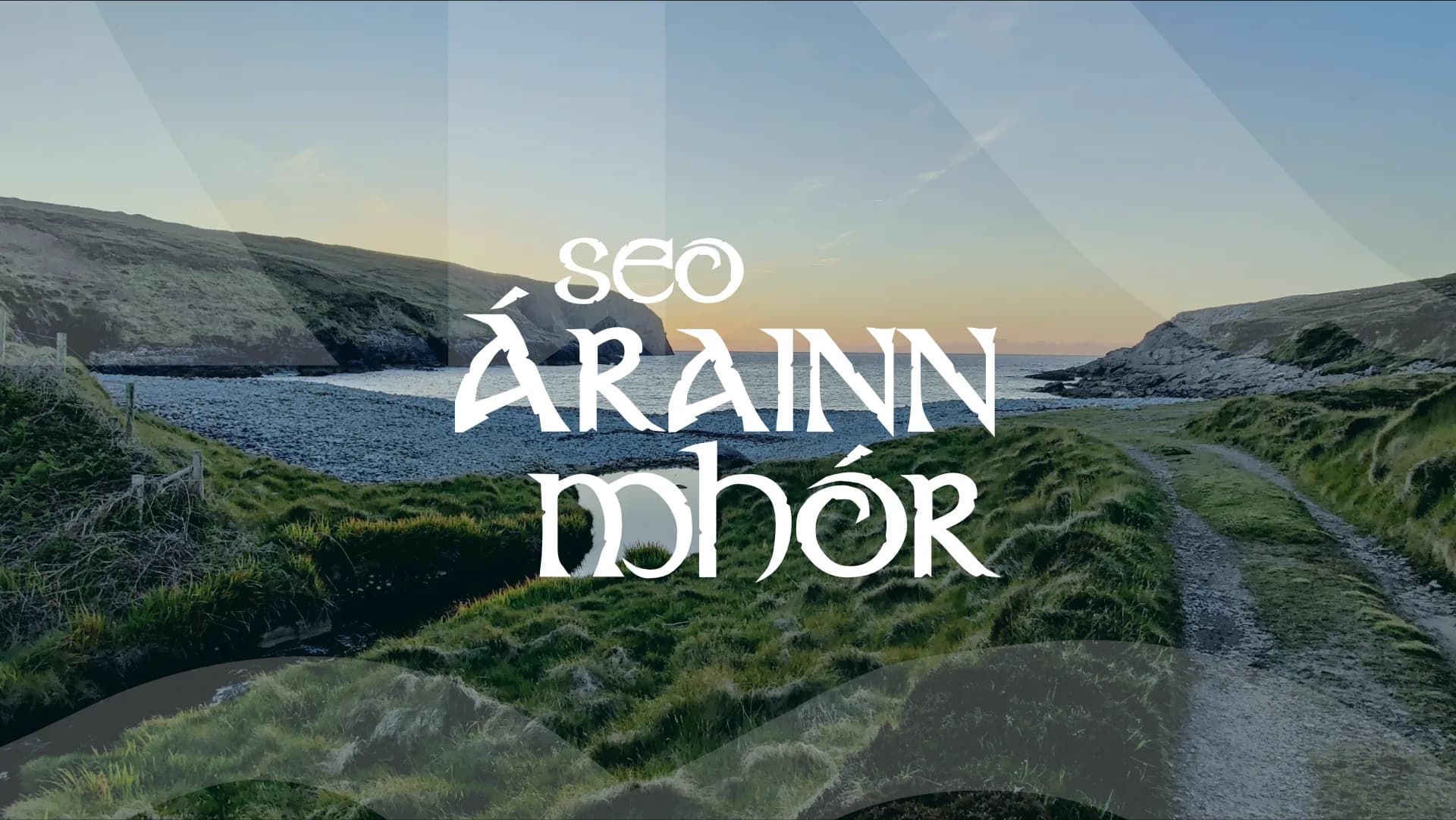 A pebble cove on Árainn Mhór at sunset, with the hand-lettered Seo Árainn Mhór wordmark